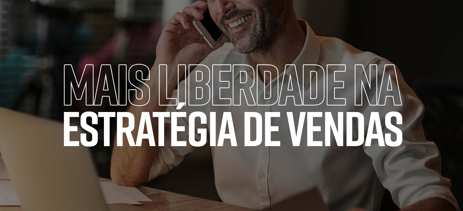 Imagem esmaecida de um empresário sorridente falando ao telefone enquanto observa seu laptop. Em primeiro plano há escrito "Mais liberdade na estratégia de vendas" citando a tela de promoções especiais do Shop 9.